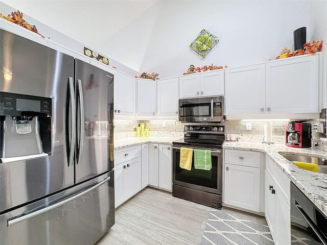7518 Mediterranean Ct, Hudson, FL 34667 - kitchen with appliances with stainless steel finishes, high vaulted ceiling, tasteful backsplash, white cabinets, and light stone countertops
