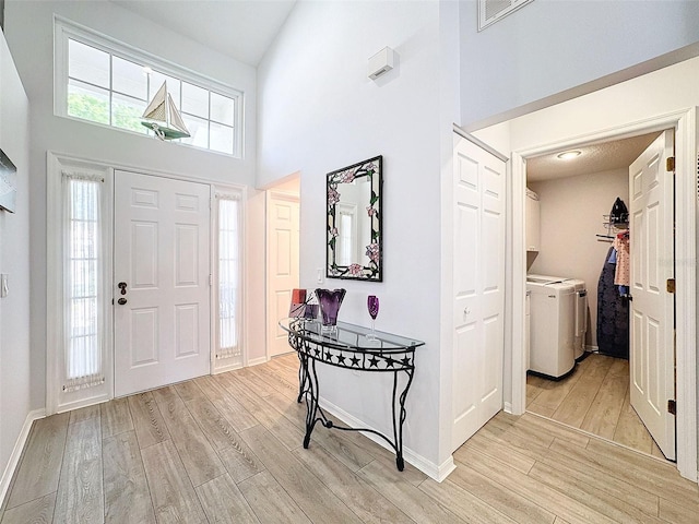 7518 Mediterranean Ct, Hudson, FL 34667 - entrance foyer with washer and dryer, light wood-style floors, and a towering ceiling