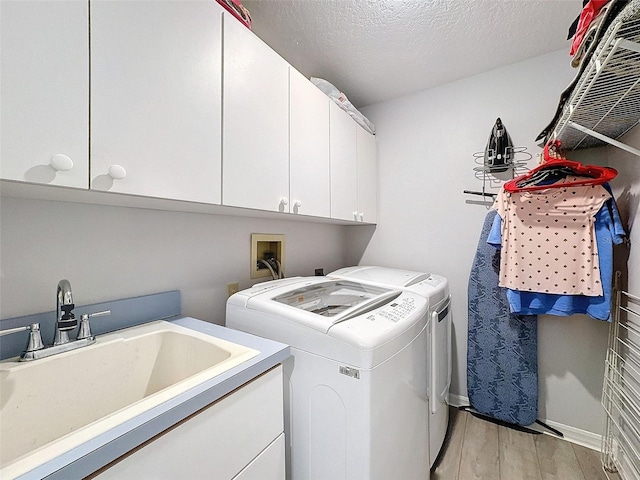 7518 Mediterranean Ct, Hudson, FL 34667 - laundry area featuring cabinet space, washing machine and clothes dryer, light wood-style flooring, and a textured ceiling