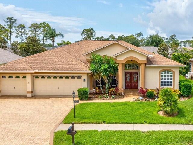 11144 Brambleleaf Way, Hudson, FL 34667 - ranch-style house featuring decorative driveway, stucco siding, an attached garage, a front yard, and a shingled roof