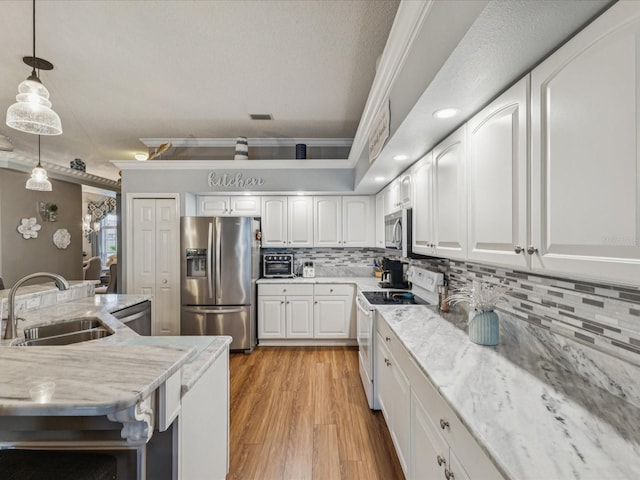 11144 Brambleleaf Way, Hudson, FL 34667 - kitchen with stainless steel appliances, crown molding, white cabinetry, pendant lighting, and backsplash