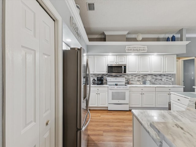 11144 Brambleleaf Way, Hudson, FL 34667 - kitchen featuring stainless steel appliances, ornamental molding, white cabinetry, decorative backsplash, and light wood finished floors