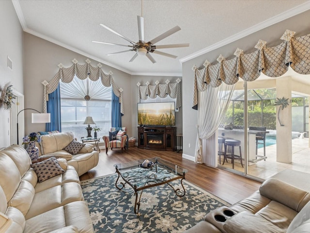 11144 Brambleleaf Way, Hudson, FL 34667 - living room featuring ceiling fan, ornamental molding, wood finished floors, a textured ceiling, and a warm lit fireplace