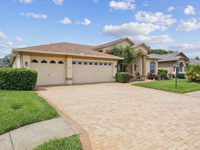 11144 Brambleleaf Way, Hudson, FL 34667 - ranch-style house featuring stucco siding, an attached garage, decorative driveway, and a front yard
