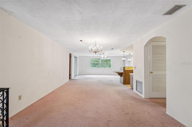8340 Saint Marks Ct, Hudson, FL 34667 - unfurnished living room with carpet, a chandelier, a textured ceiling, and arched walkways