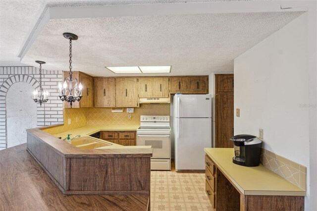 8340 Saint Marks Ct, Hudson, FL 34667 - kitchen with white appliances, under cabinet range hood, a peninsula, light floors, and a textured ceiling