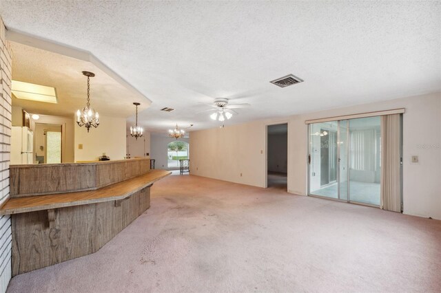 8340 Saint Marks Ct, Hudson, FL 34667 - unfurnished living room featuring light carpet, a chandelier, a ceiling fan, and a textured ceiling