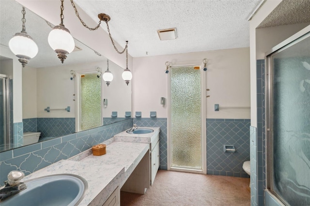 8340 Saint Marks Ct, Hudson, FL 34667 - bathroom featuring tile walls, wainscoting, a stall shower, vanity, and a textured ceiling