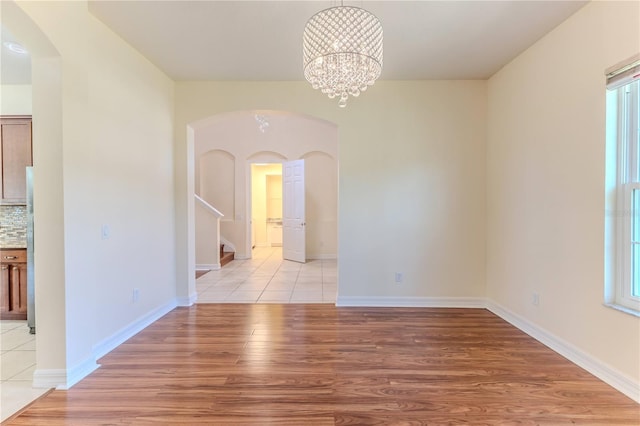 13772 Dunwoody Dr, Spring Hill, FL 34609 - unfurnished dining area featuring arched walkways, light wood-style floors, stairs, and a chandelier
