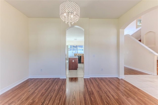 13772 Dunwoody Dr, Spring Hill, FL 34609 - spare room with arched walkways, light wood finished floors, and a chandelier