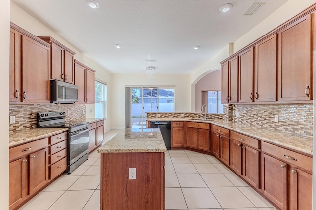 13772 Dunwoody Dr, Spring Hill, FL 34609 - kitchen featuring appliances with stainless steel finishes, arched walkways, tasteful backsplash, a peninsula, and light stone counters