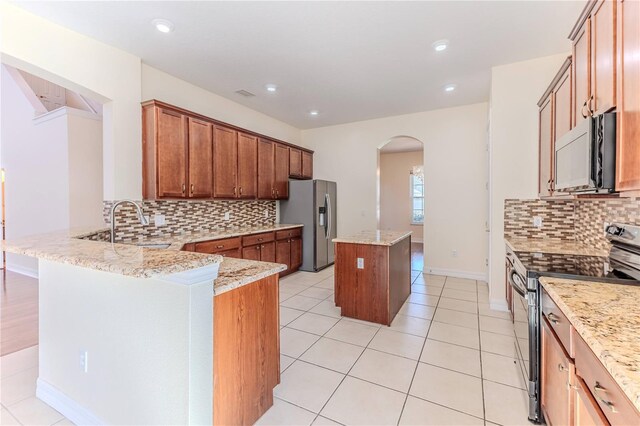 13772 Dunwoody Dr, Spring Hill, FL 34609 - kitchen with appliances with stainless steel finishes, arched walkways, a kitchen island, backsplash, and a peninsula