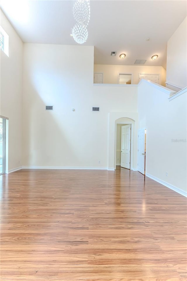 13772 Dunwoody Dr, Spring Hill, FL 34609 - spare room with healthy amount of natural light, light wood-style floors, a chandelier, arched walkways, and a high ceiling