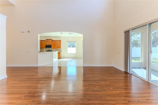 13772 Dunwoody Dr, Spring Hill, FL 34609 - unfurnished living room with a towering ceiling, light wood-style floors, and arched walkways
