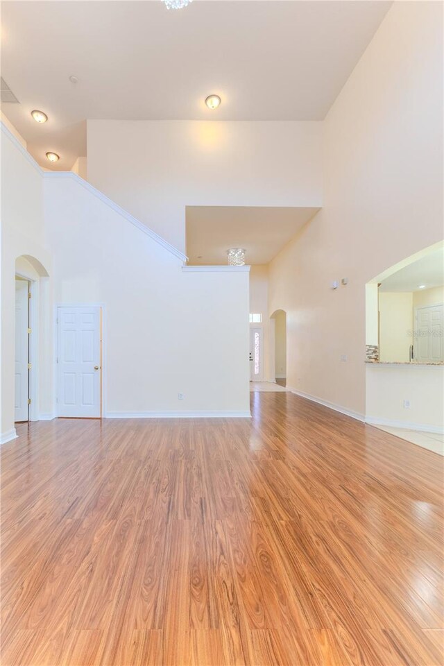 13772 Dunwoody Dr, Spring Hill, FL 34609 - unfurnished living room featuring arched walkways, high vaulted ceiling, and light wood-type flooring