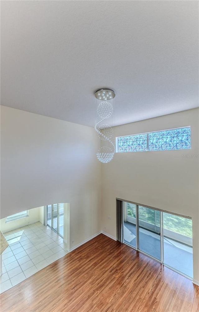 13772 Dunwoody Dr, Spring Hill, FL 34609 - spare room featuring a chandelier, wood finished floors, plenty of natural light, and a high ceiling