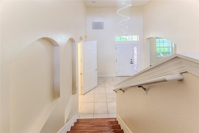 13772 Dunwoody Dr, Spring Hill, FL 34609 - stairway featuring a high ceiling, tile patterned floors, arched walkways, and a chandelier