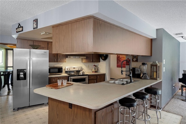 1376 Fayetteville Dr, Spring Hill, FL 34609 - kitchen with stainless steel appliances, a textured ceiling, a peninsula, under cabinet range hood, and a kitchen bar