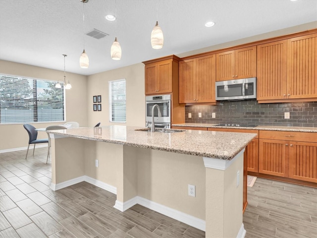 19326 Long Lake Ranch Blvd, Lutz, FL 33558 - kitchen with appliances with stainless steel finishes, backsplash, an island with sink, wood tiled floors, and light stone countertops