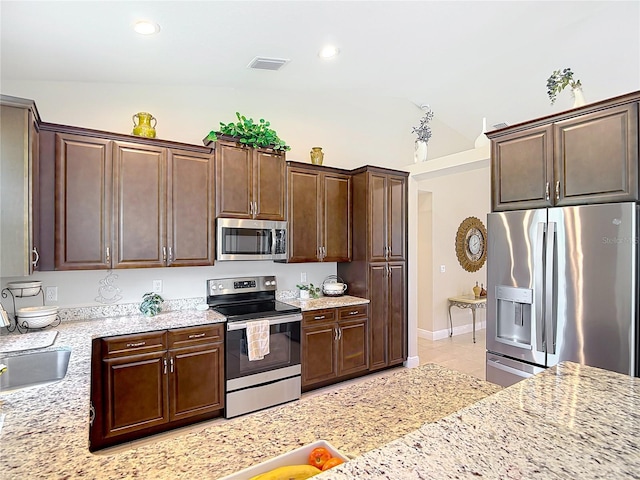 12323 House Finch, Weeki Wachee, FL 34614 - kitchen with appliances with stainless steel finishes, lofted ceiling, light stone counters, dark brown cabinets, and recessed lighting