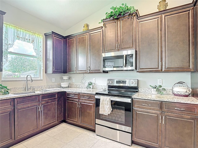 12323 House Finch, Weeki Wachee, FL 34614 - kitchen with stainless steel appliances, light tile patterned flooring, lofted ceiling, light stone countertops, and dark brown cabinetry