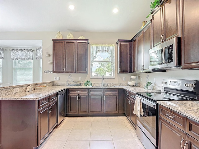 12323 House Finch, Weeki Wachee, FL 34614 - kitchen with stainless steel appliances, a peninsula, light stone counters, dark brown cabinets, and recessed lighting