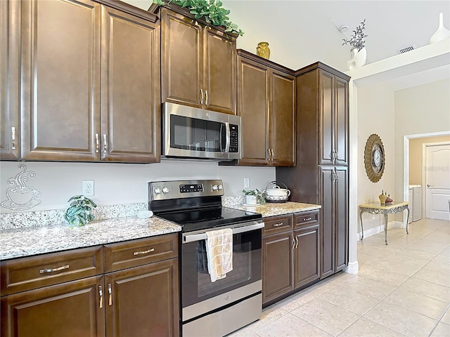 12323 House Finch, Weeki Wachee, FL 34614 - kitchen with appliances with stainless steel finishes, light tile patterned floors, light stone countertops, and dark brown cabinetry