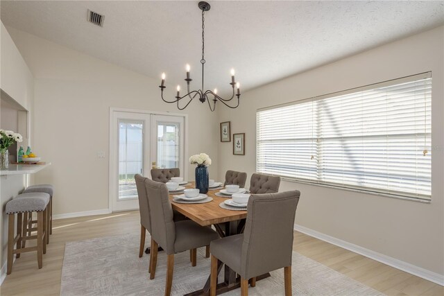 4752 Weasel Dr, New Port Richey, FL 34653 - dining room with light wood finished floors, a chandelier, french doors, and vaulted ceiling