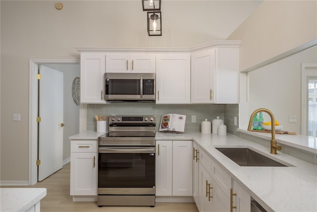 4752 Weasel Dr, New Port Richey, FL 34653 - kitchen featuring stainless steel appliances, decorative backsplash, white cabinets, and light stone counters