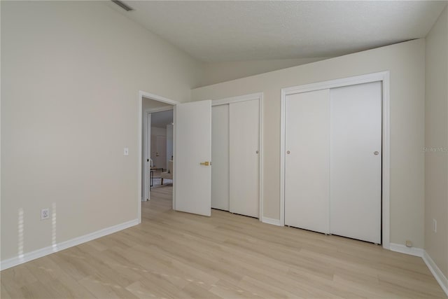 4752 Weasel Dr, New Port Richey, FL 34653 - unfurnished bedroom featuring two closets, lofted ceiling, and light wood-type flooring
