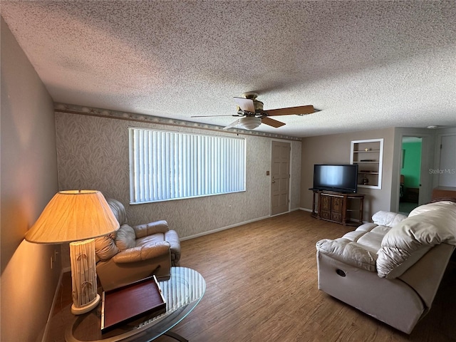 8312 Split Rail Ln, Hudson, FL 34667 - living area featuring ceiling fan, wood finished floors, a textured ceiling, wallpapered walls, and built in features