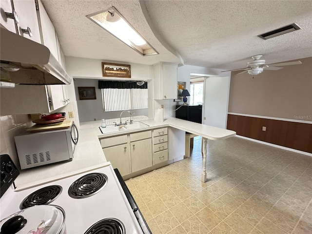 8312 Split Rail Ln, Hudson, FL 34667 - kitchen featuring under cabinet range hood, ceiling fan, a textured ceiling, light countertops, and a peninsula