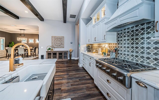 4197 Glade Wood Loop, New Port Richey, FL 34655 - kitchen featuring stainless steel gas stovetop, premium range hood, light stone countertops, white cabinets, and beamed ceiling