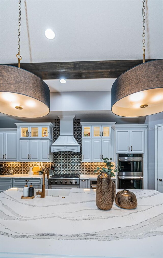 4197 Glade Wood Loop, New Port Richey, FL 34655 - detailed view of custom exhaust hood, stainless steel double oven, decorative backsplash, glass insert cabinets, and pendant lighting