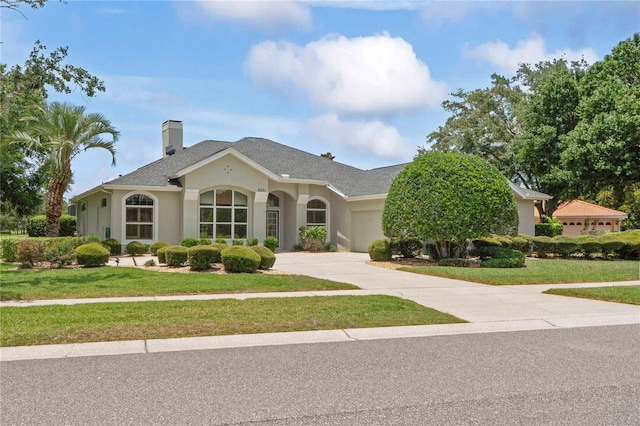 4351 Mallard Lake Dr, Spring Hill, FL 34609 - view of front of home with a garage, stucco siding, a front yard, concrete driveway, and a chimney