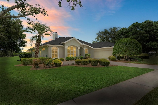 4351 Mallard Lake Dr, Spring Hill, FL 34609 - view of front facade featuring a yard, stucco siding, a garage, concrete driveway, and a chimney