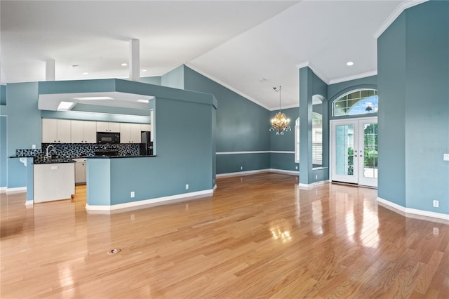 4351 Mallard Lake Dr, Spring Hill, FL 34609 - unfurnished living room featuring a chandelier, high vaulted ceiling, french doors, light wood-style floors, and ornamental molding