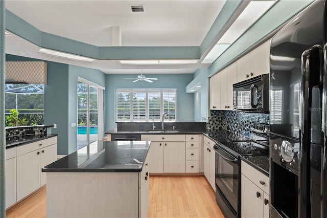 4351 Mallard Lake Dr, Spring Hill, FL 34609 - kitchen featuring black appliances, light wood-style flooring, a kitchen island, a peninsula, and decorative backsplash