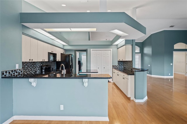 4351 Mallard Lake Dr, Spring Hill, FL 34609 - kitchen featuring black appliances, a peninsula, a breakfast bar, light wood finished floors, and recessed lighting