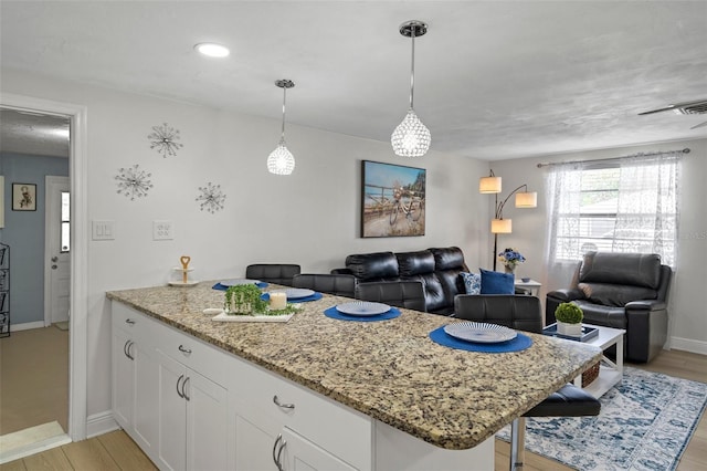 6144 Glenwood Dr, New Port Richey, FL 34653 - kitchen featuring a peninsula, open floor plan, light stone countertops, and white cabinetry