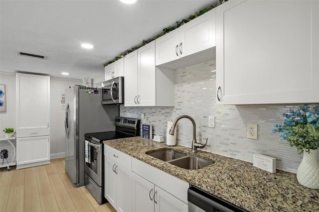 6144 Glenwood Dr, New Port Richey, FL 34653 - kitchen with appliances with stainless steel finishes, white cabinets, light stone countertops, light wood-type flooring, and tasteful backsplash