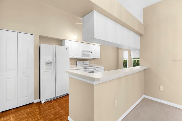 18736 Bent Pine Dr, Hudson, FL 34667 - kitchen with white appliances, white cabinets, a peninsula, light countertops, and hanging light fixtures
