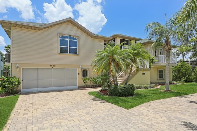 4052 Marine Pkwy, New Port Richey, FL 34652 - view of front facade featuring an attached garage, stairs, decorative driveway, a front yard, and stucco siding
