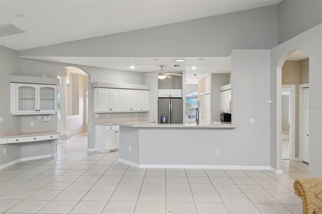 4052 Marine Pkwy, New Port Richey, FL 34652 - kitchen with stainless steel refrigerator with ice dispenser, lofted ceiling, arched walkways, white cabinets, and light tile patterned floors