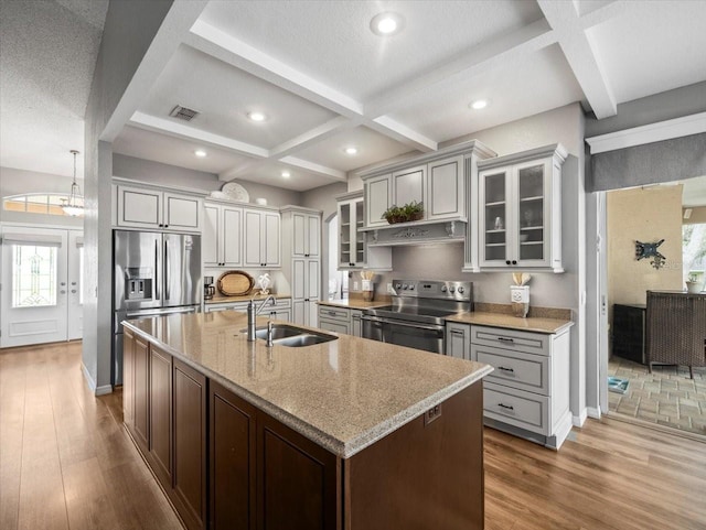 12060 Sapphire Dr, Spring Hill, FL 34609 - kitchen with stainless steel appliances, coffered ceiling, wood finished floors, a center island with sink, and healthy amount of natural light