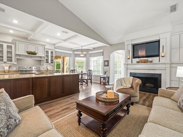 12060 Sapphire Dr, Spring Hill, FL 34609 - living area featuring light wood-type flooring, coffered ceiling, arched walkways, a fireplace, and recessed lighting