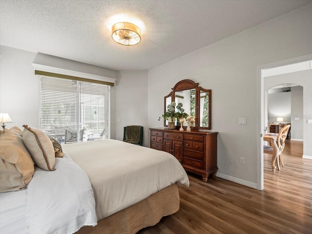 12060 Sapphire Dr, Spring Hill, FL 34609 - bedroom featuring arched walkways, wood finished floors, and a textured ceiling