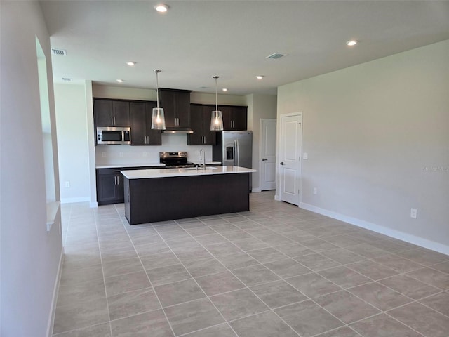 14425 Maiden Ter, Lakewood Ranch, FL 34211 - kitchen with appliances with stainless steel finishes, light countertops, a kitchen island with sink, light tile patterned floors, and decorative light fixtures