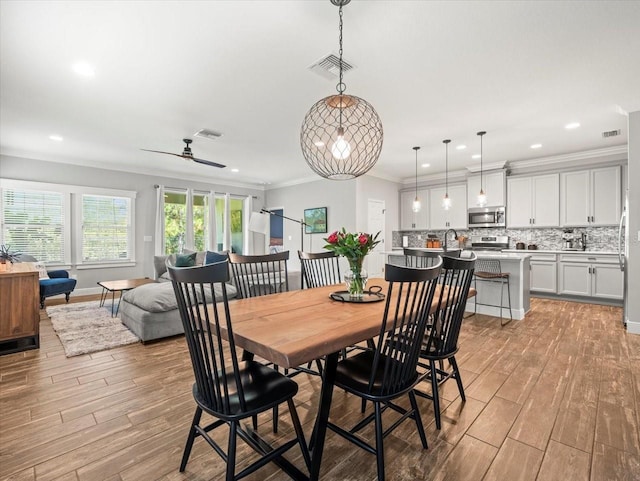 6130 Colmar Pl, Apollo Beach, FL 33572 - dining space with light wood finished floors, crown molding, ceiling fan, and recessed lighting