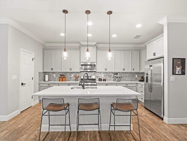 6130 Colmar Pl, Apollo Beach, FL 33572 - kitchen featuring appliances with stainless steel finishes, a breakfast bar area, wood finished floors, light countertops, and tasteful backsplash